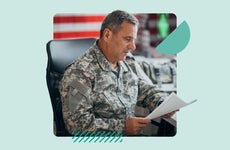 A man wearing army fatigues looks over paperwork in his office.