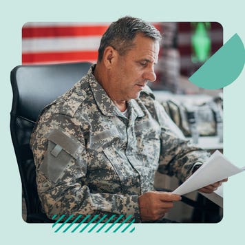 A man wearing army fatigues looks over paperwork in his office.