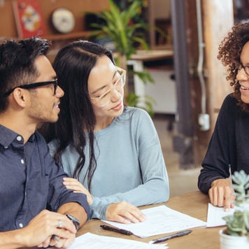 A couple speaks with an advisor at a table.