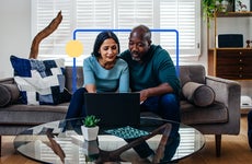 Couple sitting on a couch in front of a laptop