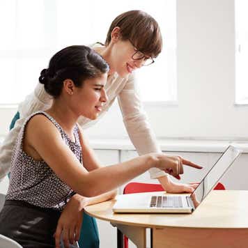Creative coworkers looking together at laptop