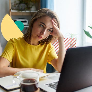 Woman sits at her table, looking discouragingly at her laptop.
