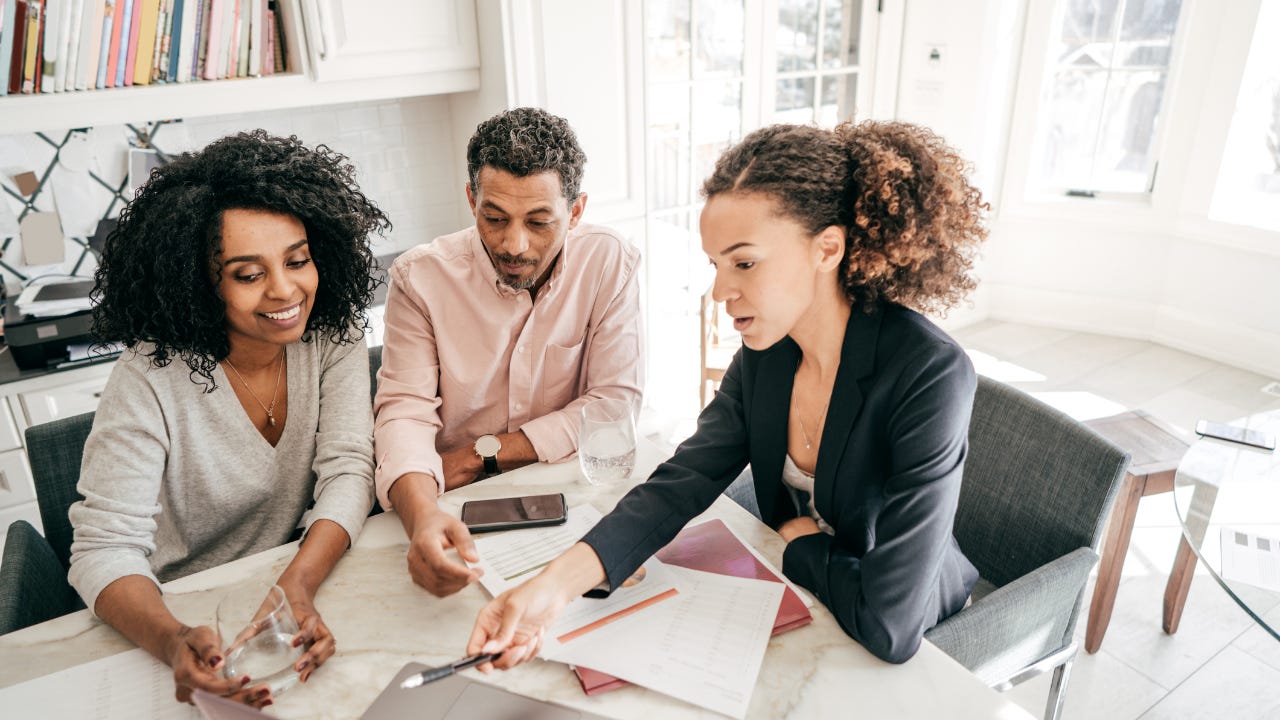 A bank rep explains financial matters to a couple.