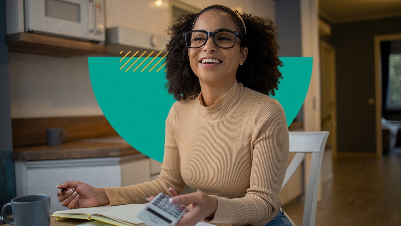 A woman wearing glasses smiles as she holds a calculator.