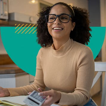 A woman wearing glasses smiles as she holds a calculator.