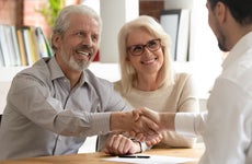 Older couple shakes hands with business loan broker