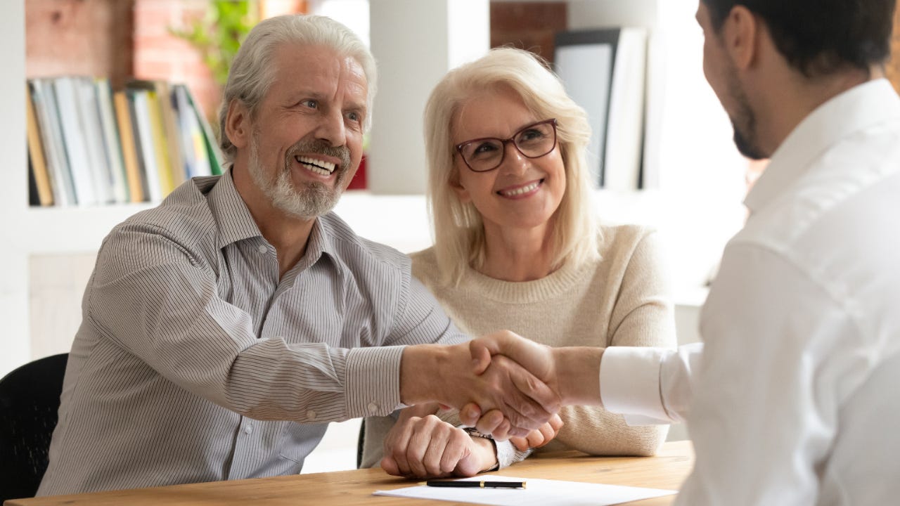 Older couple shakes hands with business loan broker
