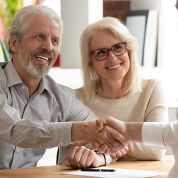Older couple shakes hands with business loan broker