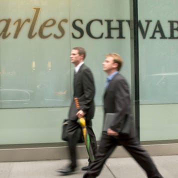 Two businessmen walk by a Charles Schwab building