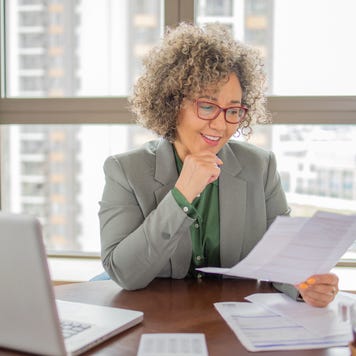 A mature woman reviewing documents in front of a computer