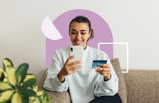 design element of a women sitting on a couch and holding a credit card and phone in each hand