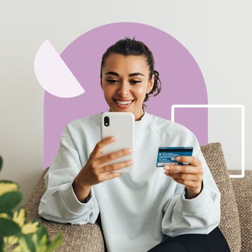 design element of a women sitting on a couch and holding a credit card and phone in each hand