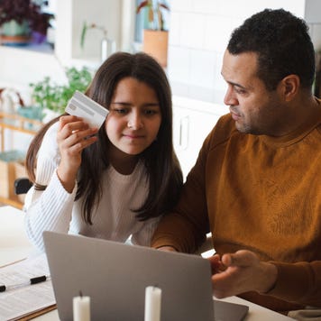 Father teaching online shopping to daughter on laptop at home