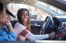 A young black woman and her mother drive a car.