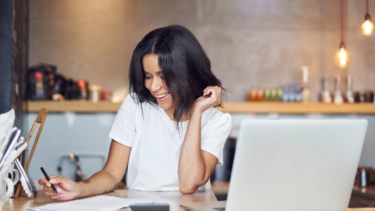 Woman filling out forms and finances with a laptop.