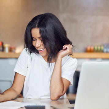Woman filling out forms and finances with a laptop.