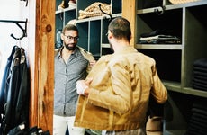 Man trying on jacket while looking in the mirror in mens clothing shop
