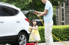 Girl helping father cleaning car
