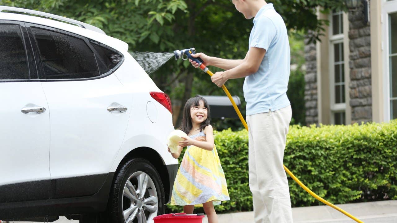 Girl helping father cleaning car