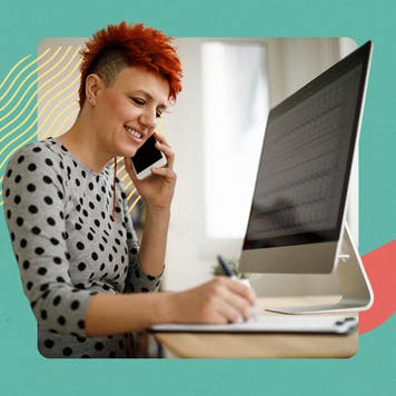 Person with short hair on the phone in front of their computer while writing something