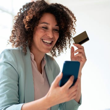 Happy businesswoman doing online payment through smart phone at workplace