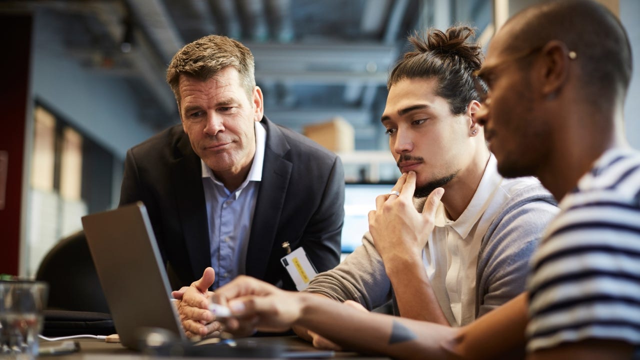 Male entrepreneur giving presentation over laptop at desk in creative office