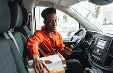 Young male driver using smart phone while sitting in delivery van
