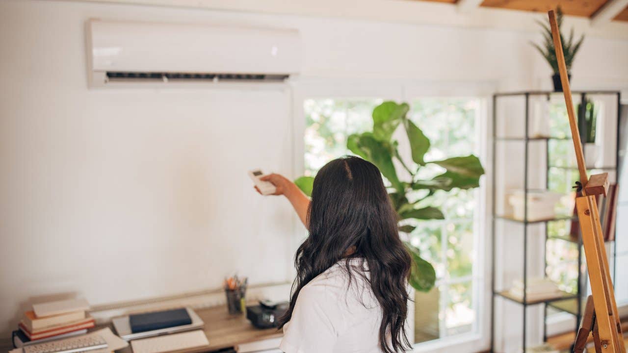 Woman turning on air conditioner