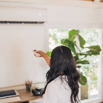Woman turning on air conditioner