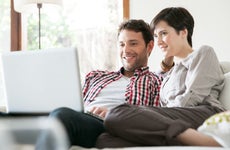 Couple sitting on sofa looking at laptop
