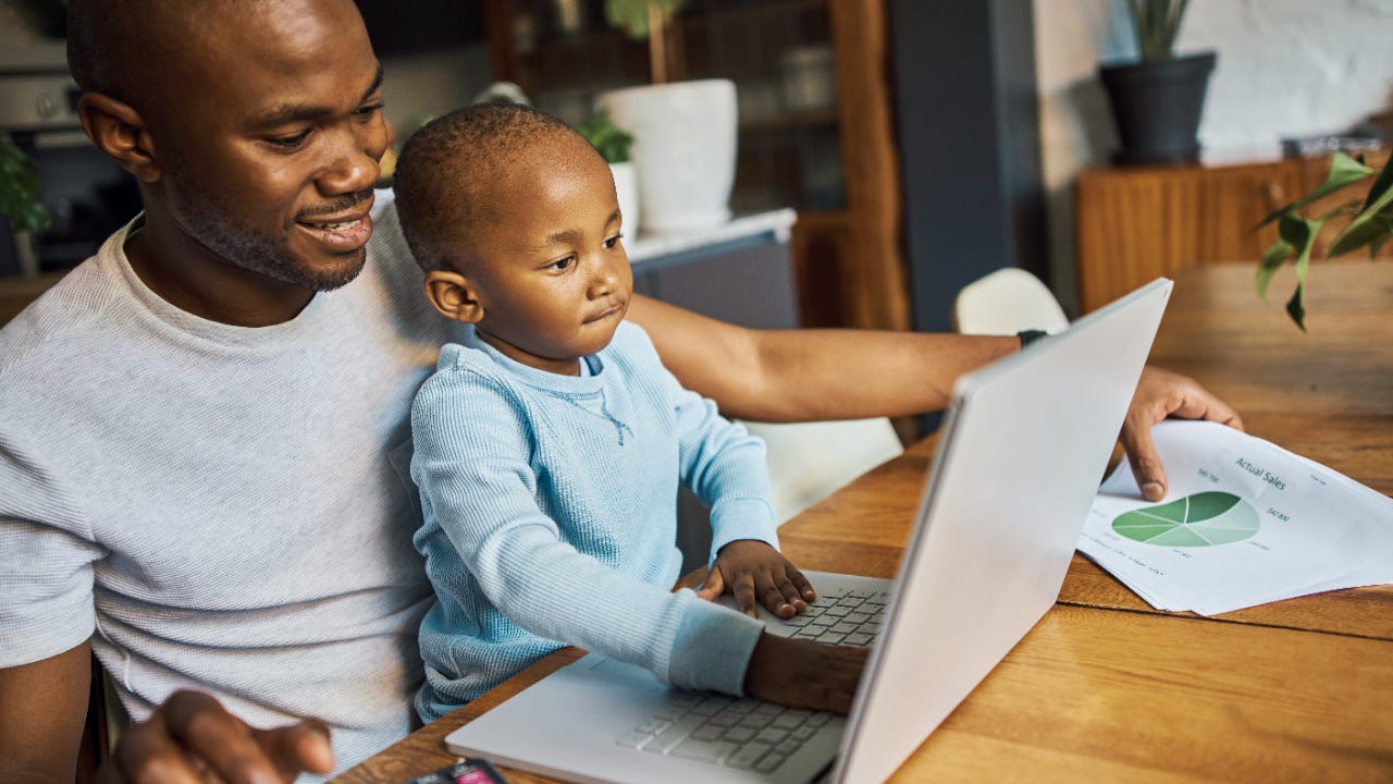 A man reviews financial documents on a laptop with his son.