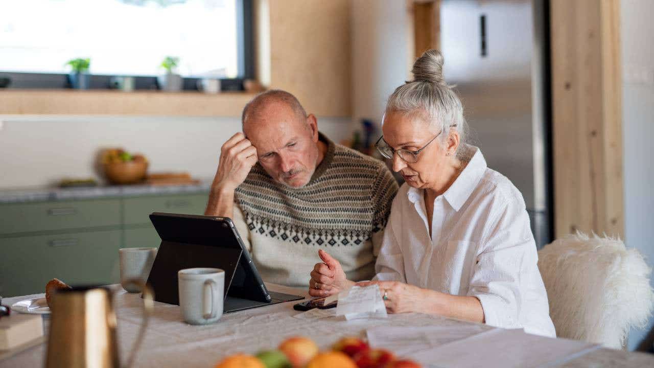 couple sitting at the kitchen table looking at digital tablet