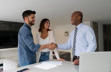 Couple buying a house and closing the deal with the Real Estate Agent with handshake