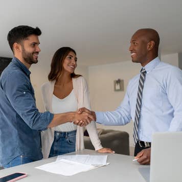 Couple buying a house and closing the deal with the Real Estate Agent with handshake