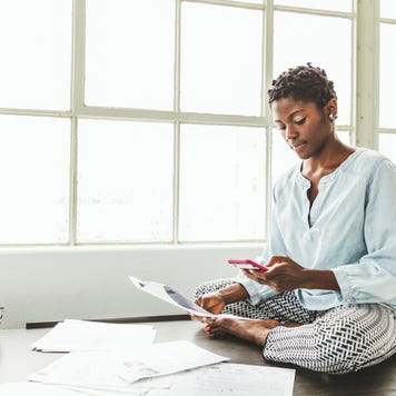 Female entrepreneur using smart phone while sitting on desk in office