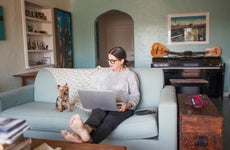 Woman sitting on couch with laptop computer
