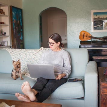 Woman sitting on couch with laptop computer