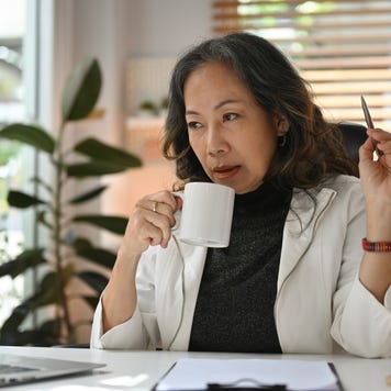 Professional elderly business woman looks stylish sip coffee during working with laptop.