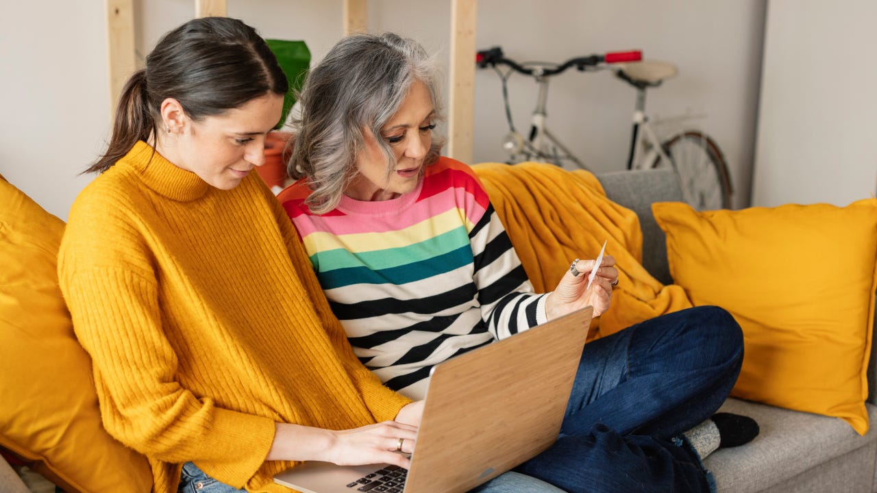 Daughter and mother shopping online with credit card on laptop