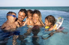 Happy parents and their kids enjoying in the swimming pool.
