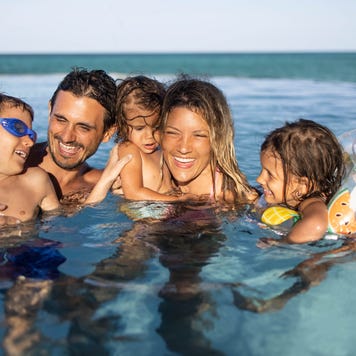 Happy parents and their kids enjoying in the swimming pool.