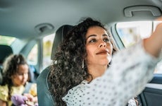 Mid adult woman adjusting rear view mirror inside a car