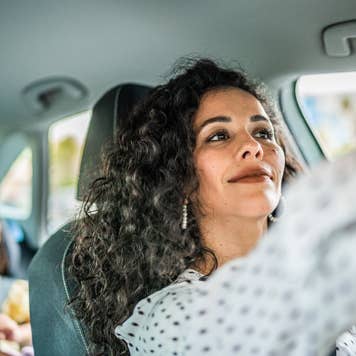 Mid adult woman adjusting rear view mirror inside a car