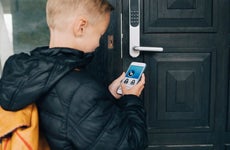 View of boy using app on smart phone to unlock house door