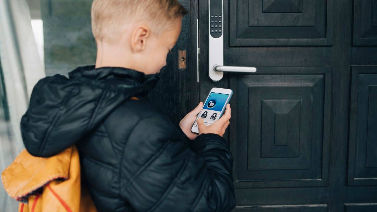 View of boy using app on smart phone to unlock house door