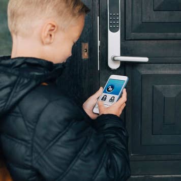 View of boy using app on smart phone to unlock house door