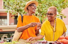 Two women shopping together at an outdoor food market