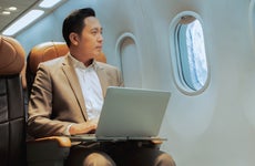 Businessman with notebook sitting inside an airplane.