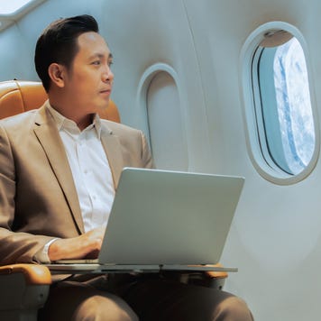 Businessman with notebook sitting inside an airplane.