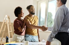 Happy black couple shaking hands with a homebuilder